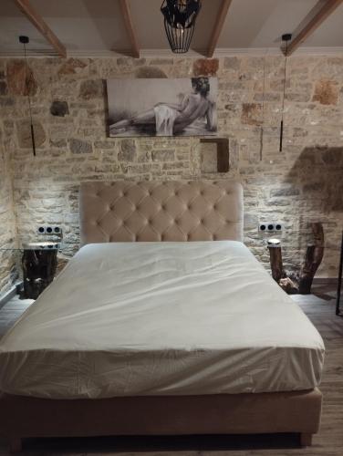 a bedroom with a large bed with a stone wall at Ekali stone house in Kalentzi