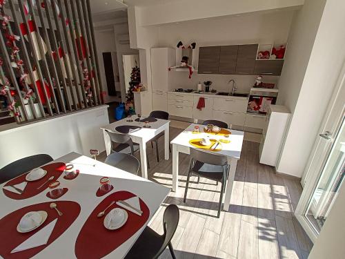 a kitchen with white tables and chairs and a kitchen with a christmas tree at Afrodite Guest House in Caserta