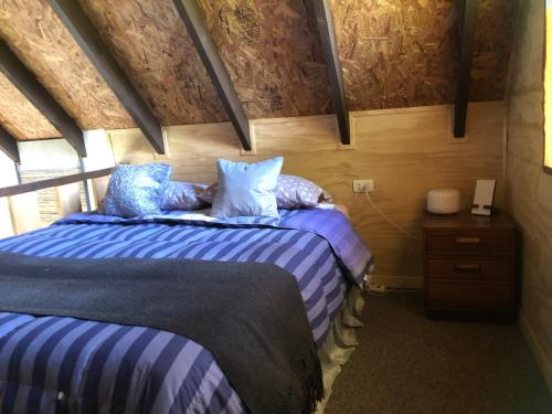 1 dormitorio con 2 camas y almohadas azules y blancas en Tiny House, Tiny Black Frutillar, en Frutillar