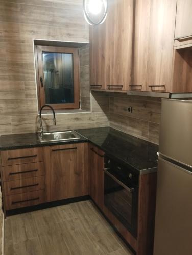 a kitchen with wooden cabinets and a sink and a refrigerator at Ekali stone house in Kalentzi