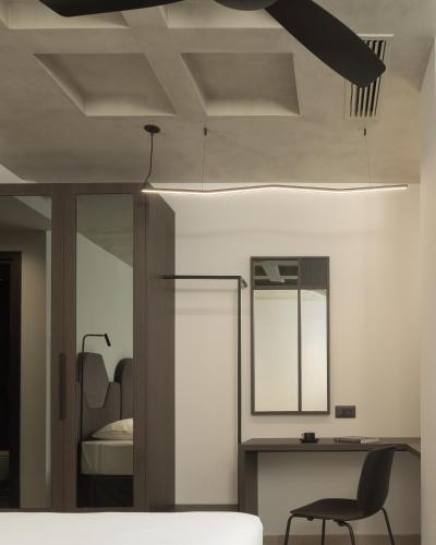 a bedroom with a bed and a chair and a mirror at Pleiades Urban Stay by Semavί in Heraklio Town