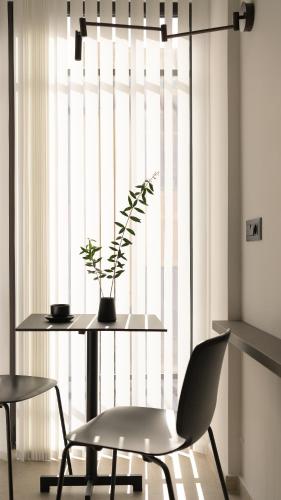 a table and chair with a plant on it in front of a window at Pleiades Urban Stay by Semavί in Heraklio Town