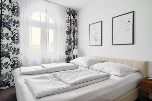 1 cama blanca con 2 almohadas y ventana en APARTAMENT PRZY RYNKU II, en Chełmno