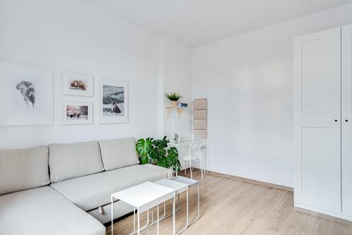 a white living room with a couch and tables at Hann Haven Apartments Ozimska 55 in Opole