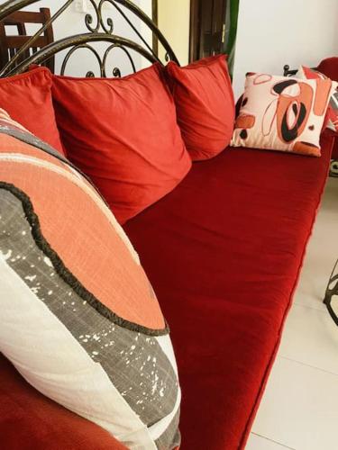 a red couch with red pillows on it at La Villa Tila in Ouoran