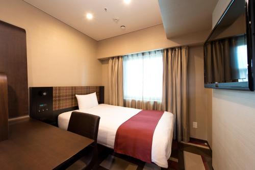 a hotel room with a bed and a window at Hotel Villa Fontaine Kobe Sannomiya in Kobe