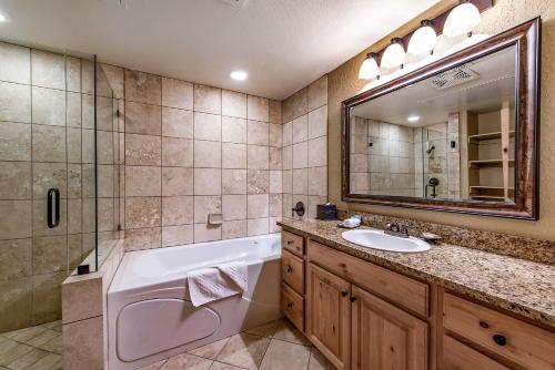 a bathroom with a tub and a sink and a mirror at Silverado Lodge by All Seasons Resort Lodging in Park City