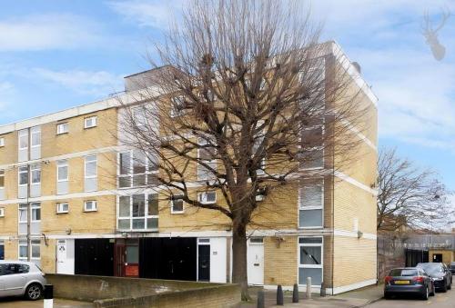 a tree in front of a brick building at Entire 3 Bedroom Luxury Apartment in London with Private Balcony in London