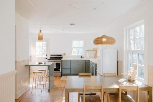 a kitchen with a table and a refrigerator at The Bungalow Loft by WB Abodes in Wrightsville Beach