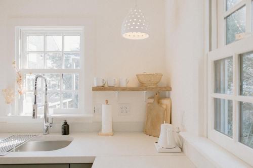 The Bungalow Loft by WB Abodes في رايتسفيل بيتش: مطبخ أبيض مع حوض ونافذة