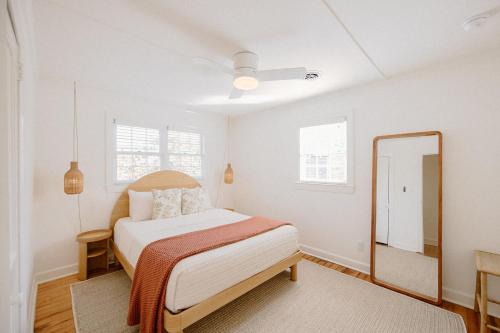 a white bedroom with a bed and a mirror at The Bungalow Loft by WB Abodes in Wrightsville Beach