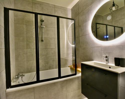 een badkamer met een bad, een wastafel en een spiegel bij Take your time in Cluses