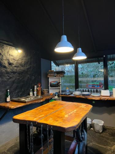 une cuisine avec une table en bois et deux lampes pendant dans l'établissement HOSTEL PEHUENIA, à El Bolsón