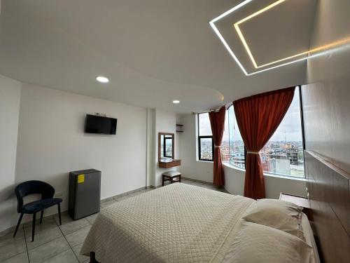 a bedroom with a bed and a large window at Hotel Torre Azul in Santo Domingo de los Colorados