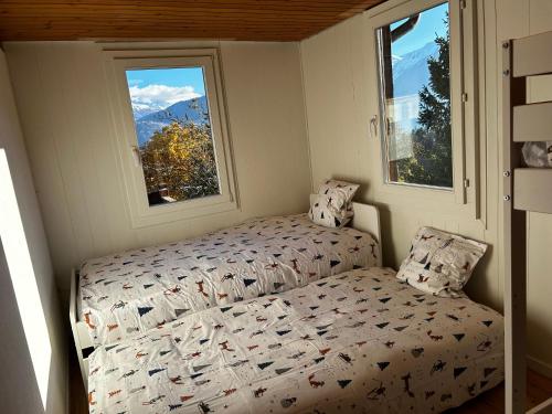 a small bedroom with a bed and two windows at SNOW NEST: Superbe cocon enneigé in Crans-Montana