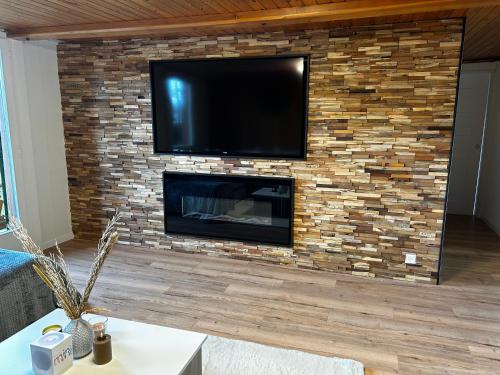 a fireplace with a flat screen tv on a brick wall at SNOW NEST: Superbe cocon enneigé in Crans-Montana