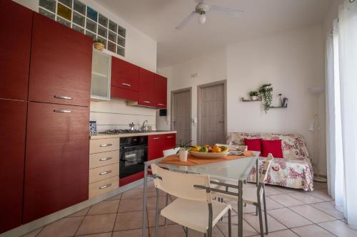 マリーナ・ディ・ラグーザにあるCapoSud - Appartamento Salgariのキッチン(赤いキャビネット、テーブル、椅子付)