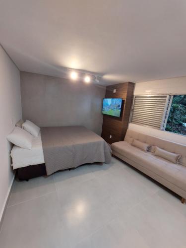 1 dormitorio pequeño con 1 cama y 1 sofá en Studio reformado - sem garagem de auto en São Vicente
