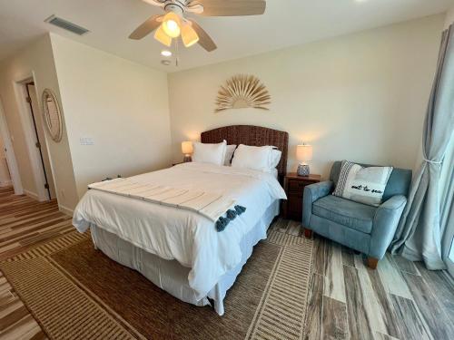 a bedroom with a large bed and a blue chair at Family Tides on LGI - Golf Cart Included in Placida