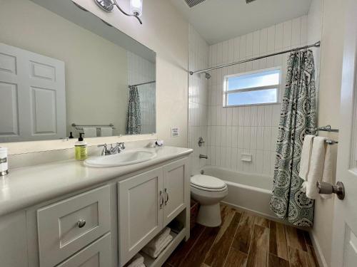 a white bathroom with a sink and a toilet at Family Tides on LGI - Golf Cart Included in Placida