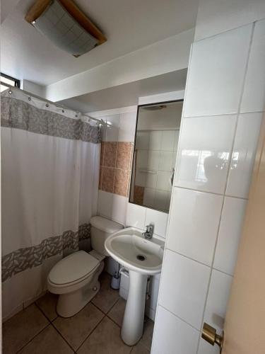 ein weißes Bad mit einem WC und einem Waschbecken in der Unterkunft Reina Isidora in Iquique