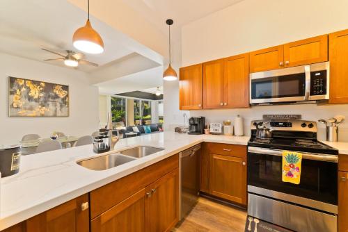 a kitchen with wooden cabinets and a stove top oven at Hilton Pool Pass Included - Luxe Villa in Waikoloa