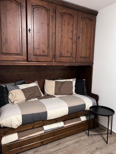 a bed with wooden cabinets and a table in a room at da Robi appartamento fronte piste in Borgata Sestriere