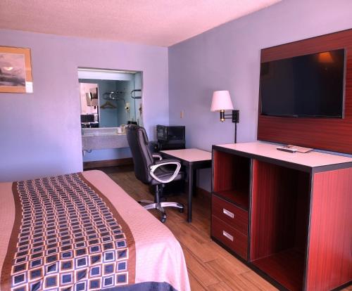 a hotel room with a bed and a desk with a television at Rodeway Inn in Richland