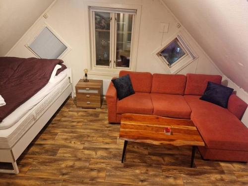 sala de estar con sofá rojo y cama en Smaller apartment next to bridge, en Tromsø