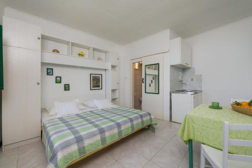 a white bedroom with a bed and a table at Apartments Nada in Bol