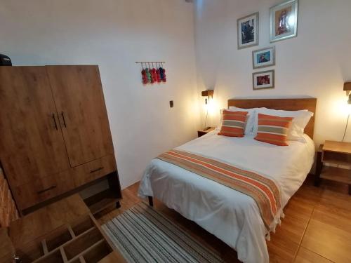 - une chambre avec un grand lit et une armoire en bois dans l'établissement Suites del Barrio, à San Cristóbal de Las Casas