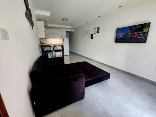 uma sala de estar com um sofá preto num quarto em F&E Apartment em Necochea