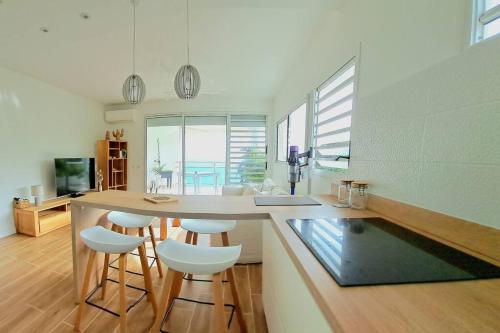 a kitchen with a counter and stools in a room at Bleu Caraïbes. Gosier, spacieux 2 pièces, vue mer in Le Gosier