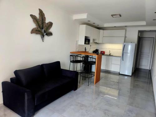 a living room with a black couch and a kitchen at F&E Apartment in Necochea