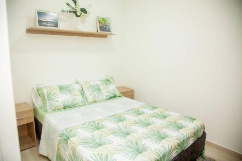 a bedroom with a bed with a green and white comforter at Acogedor apartamento moderno para 6 personas in Cali