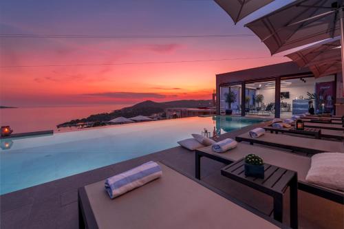 a villa with a swimming pool with a sunset at Apartments Villa Poco Loco in Mlini