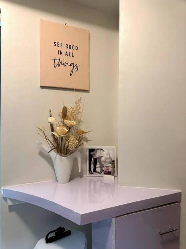 a vase of flowers sitting on a shelf in a room at New & Spacious Unit in QC w/ Wifi & Netflix in Manila