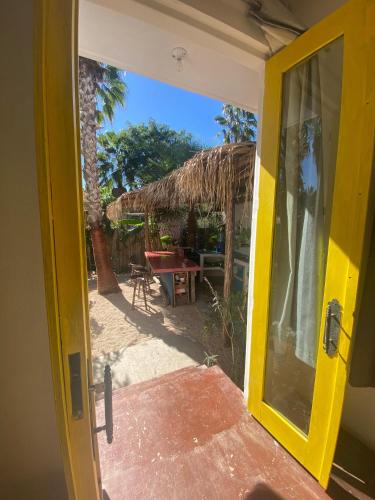 an open door to a patio with a table and a straw hut at La Sardina in Todos Santos