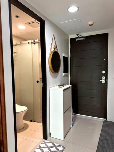a bathroom with a toilet and a black door at New & Spacious Unit in QC w/ Wifi & Netflix in Manila