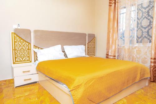 ein Schlafzimmer mit einem Bett mit gelber Tagesdecke und einem Fenster in der Unterkunft Epson’s Villas in Brufut