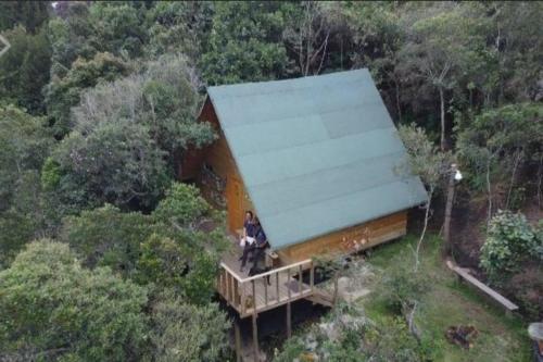 a person sitting on a porch of a house at Hermosa cabaña con huerta - Casa verde in Medellín