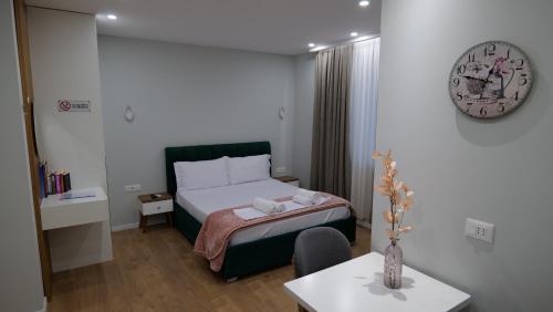 ein Schlafzimmer mit einem Bett, einem Tisch und einer Uhr in der Unterkunft Kristi Apartments 01 in Tirana