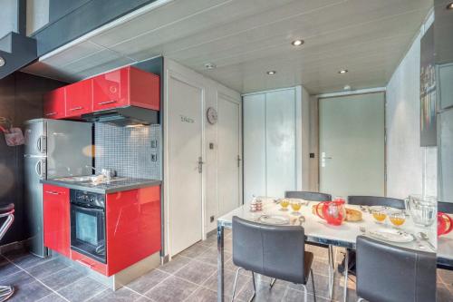 une cuisine avec des placards rouges et une table avec des chaises dans l'établissement Le Commandant - Paul Mistral - Stade des Alpes, à Grenoble