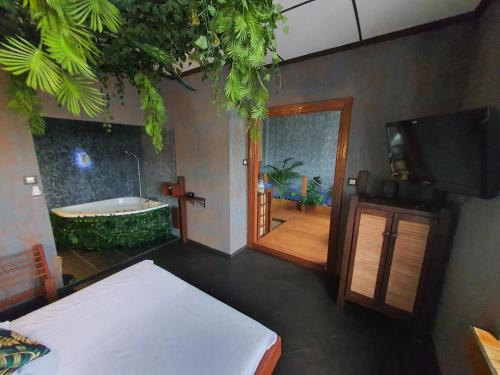 a room with a tub and a bed and a television at Tropicana Jacuzzi Apartment in Kraków