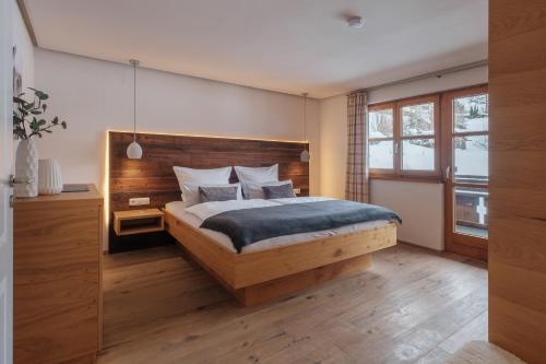Haus Bergheimat في اوبرستدورف: غرفة نوم مع سرير مع اللوح الأمامي الخشبي