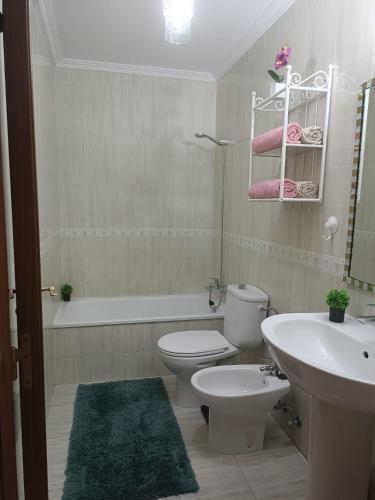 a bathroom with a toilet and a sink and a tub at Apartament MaxMax in Los Abrigos
