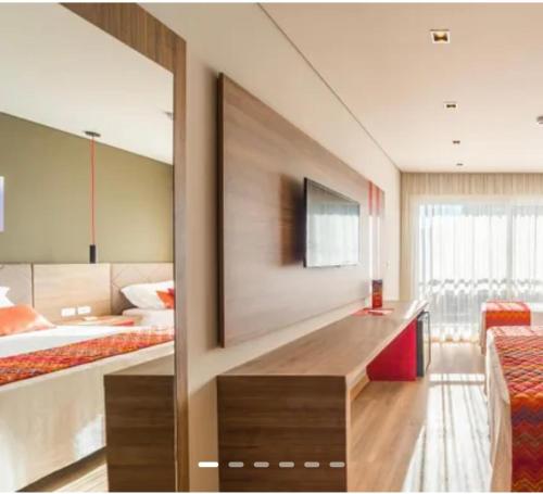 a hotel room with a bed and a television at Quarto no Hotel Laghetto Stillo da Borges in Gramado
