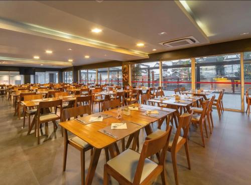 un restaurant avec des tables et des chaises en bois ainsi que des fenêtres dans l'établissement Quarto no Hotel Laghetto Stillo da Borges, à Gramado