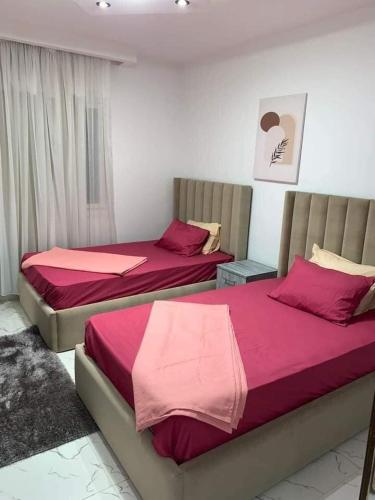 duas camas num quarto com lençóis vermelhos em شقه سكنيه مفروشه بكورنيش المعادي no Cairo