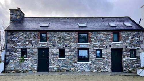 Casa de piedra con puertas y ventanas negras en Bill's Barns Apartment 2 en Kenmare
